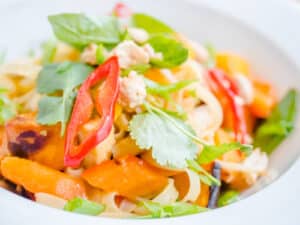 A bowl of freshly prepared carrot salad mixed with jalapeno garnished with herbs and spices.