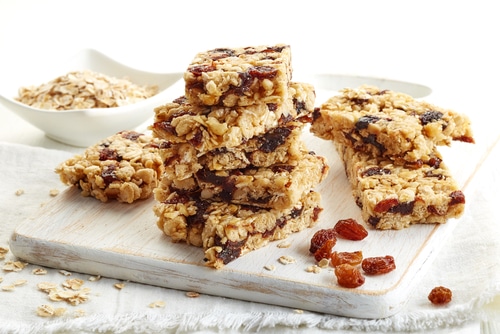 Granola bar with raisins on white wooden background