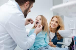 A dentist examining a childs teeth and probe during a dental checkup.