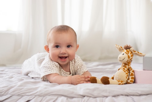 Adorable laugh with 2 teeth smile a baby takes a toy giraffes and learns to crawl