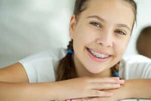 Young girl smiling during the first few weeks of her traditional dental braces treatment.