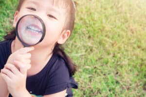 Young child showing their baby teeth off, at risk of having the damaged or knocked loose.